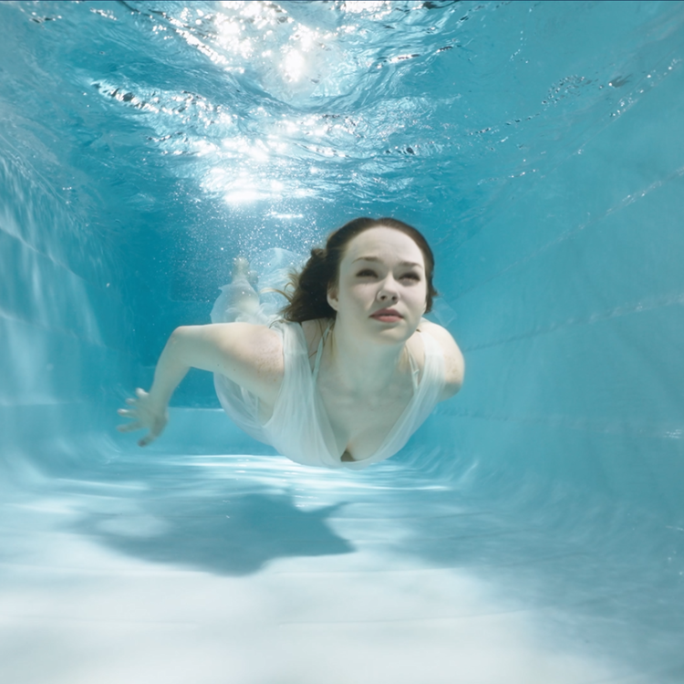 Vrouw onder water bij het zwembad