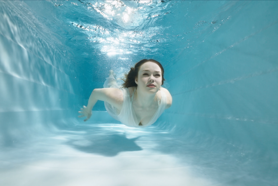 Vrouw onder water bij het zwembad